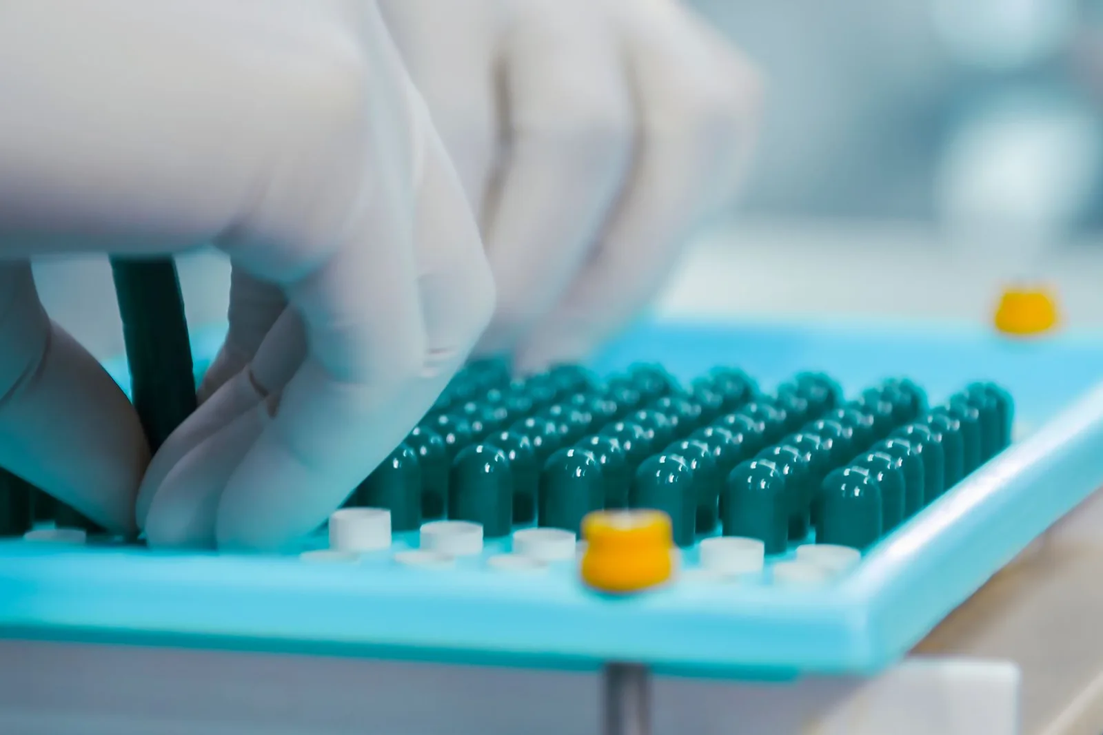 Product liability expert witness — Gloved hands inspecting capsules in a laboratory