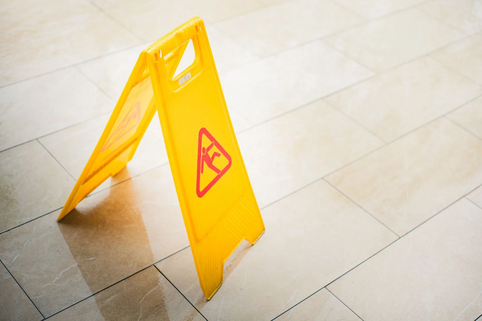 Slip and fall expert witness — Wet floor warning sign on a polished walkway