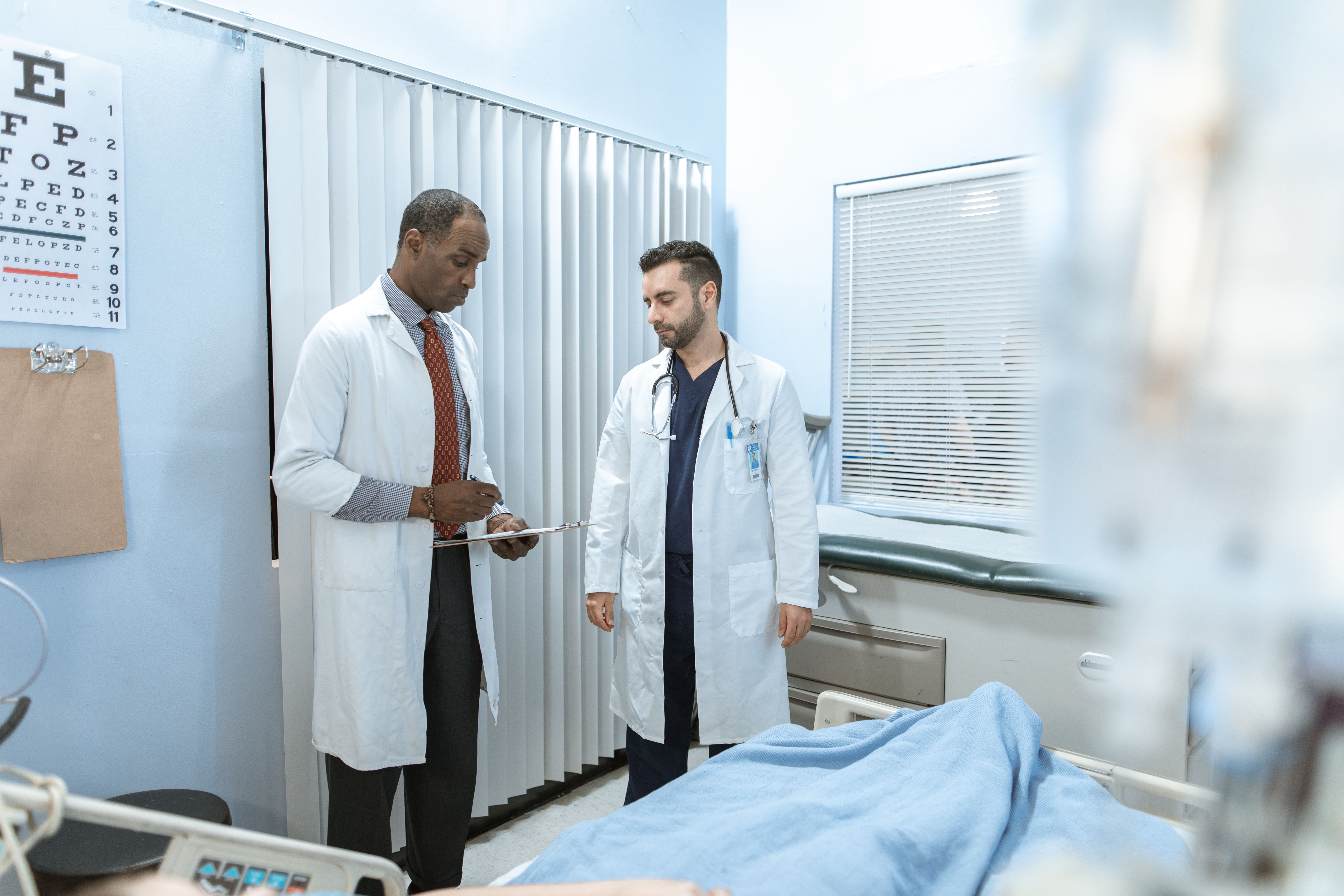 Condition and prognosis report — Two clinicians reviewing a patient's medical chart in a hospital setting
