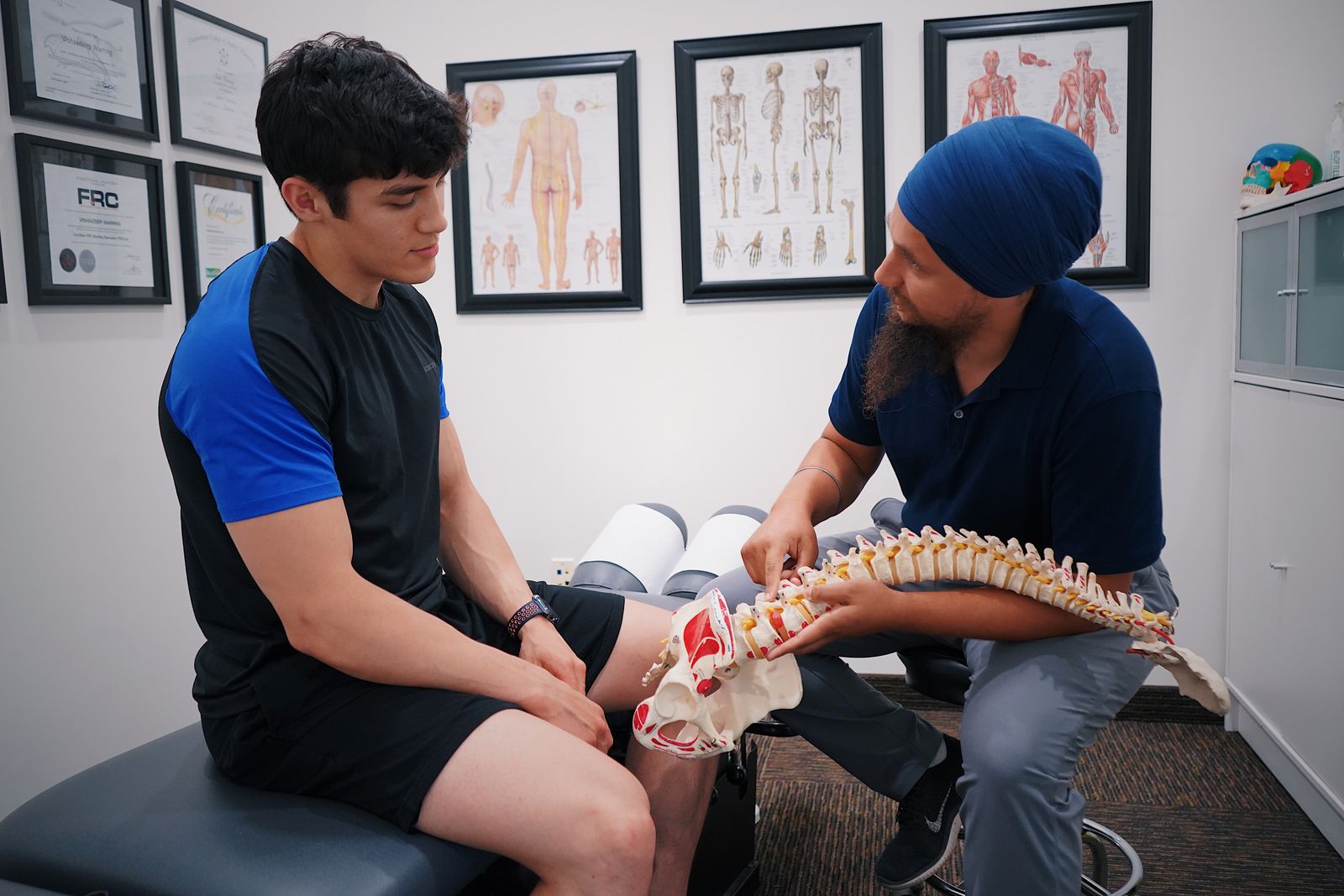 Clinician explaining a spine model during consultation, the assessment pain management expert witnesses provide