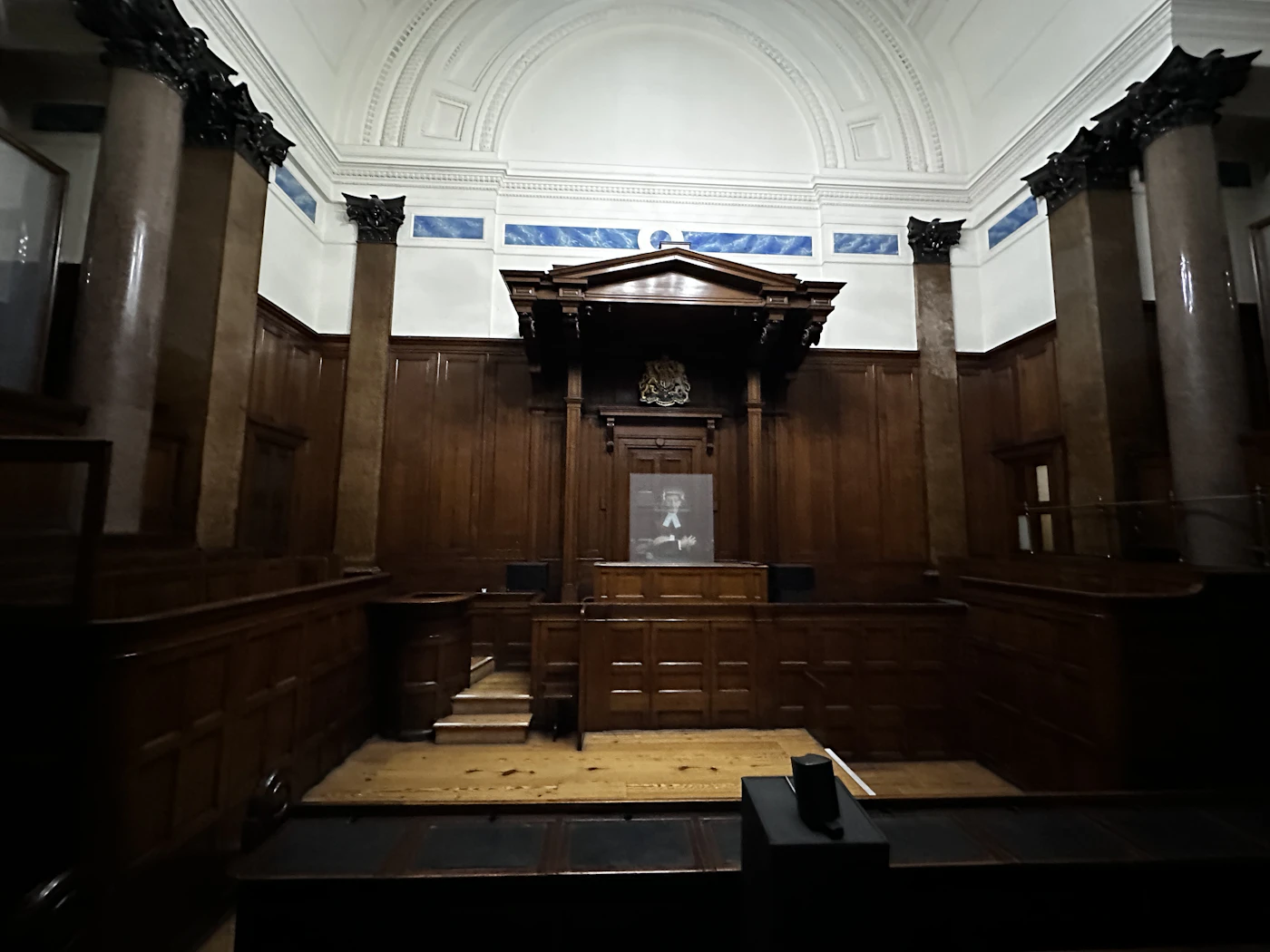 Empty courtroom with wood panelling and a judge's bench