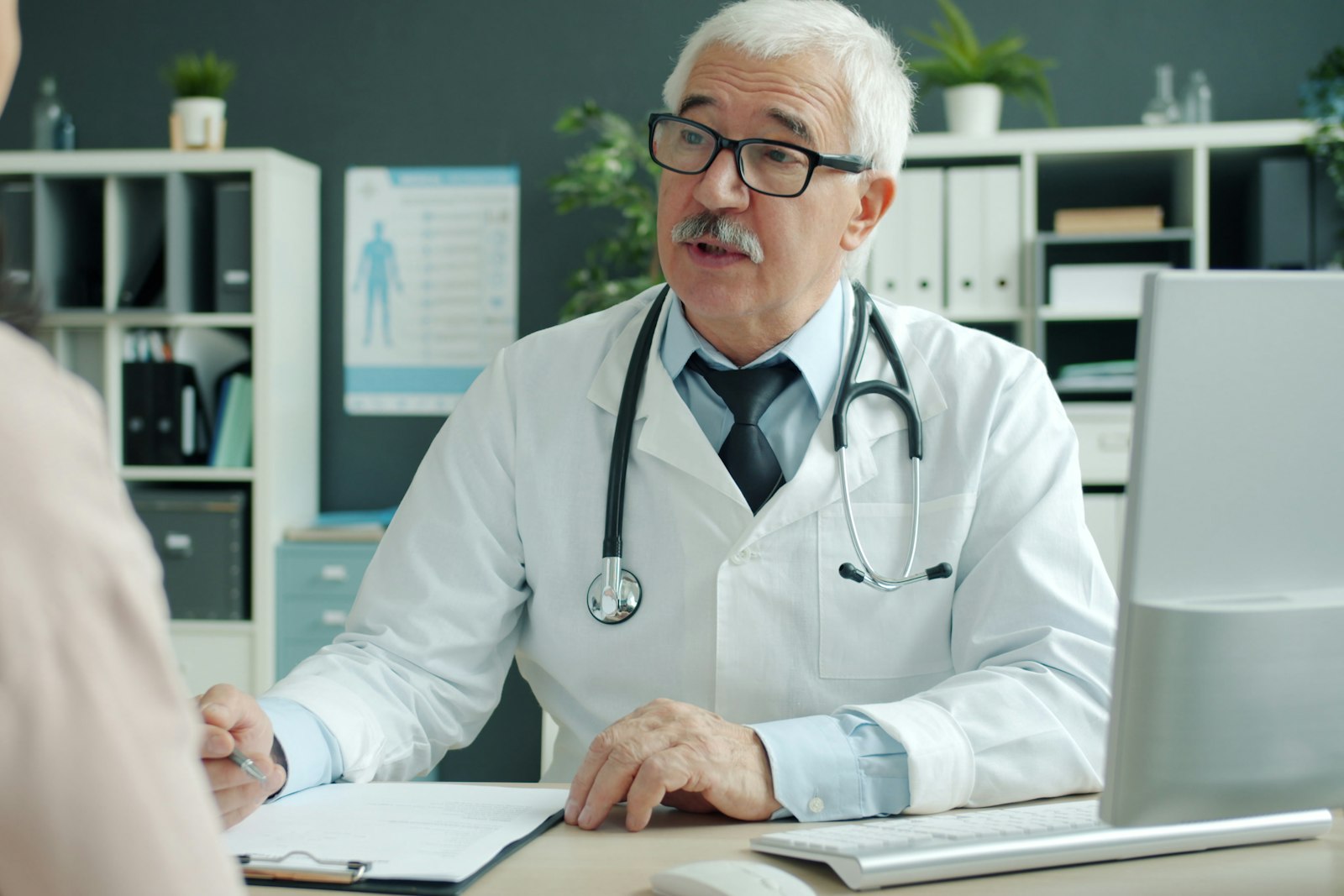 General practitioner consulting a patient at a surgery desk, the care general practice expert witnesses review