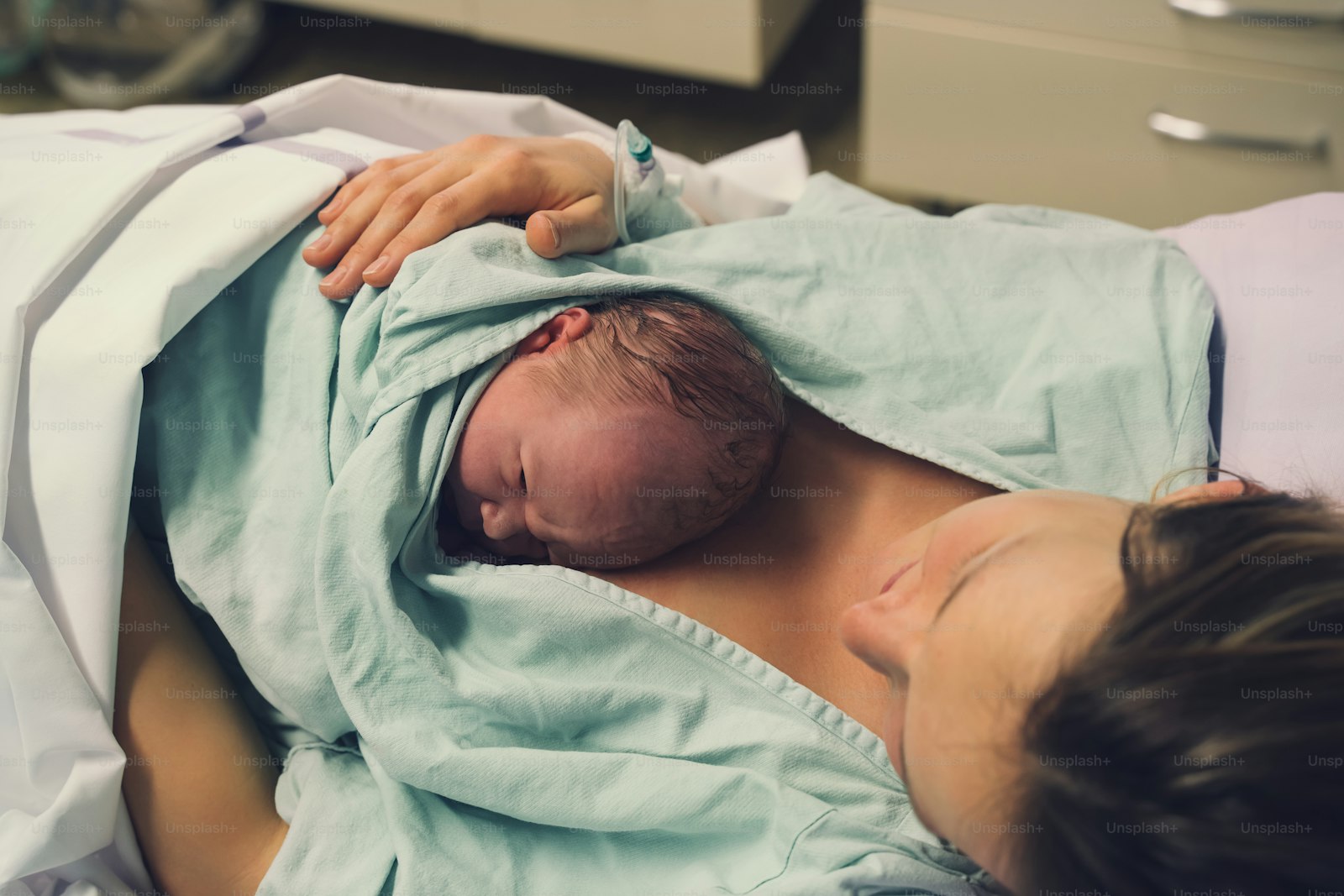 Clinician handing a newborn to the mother after delivery, the care obstetrics expert witnesses examine