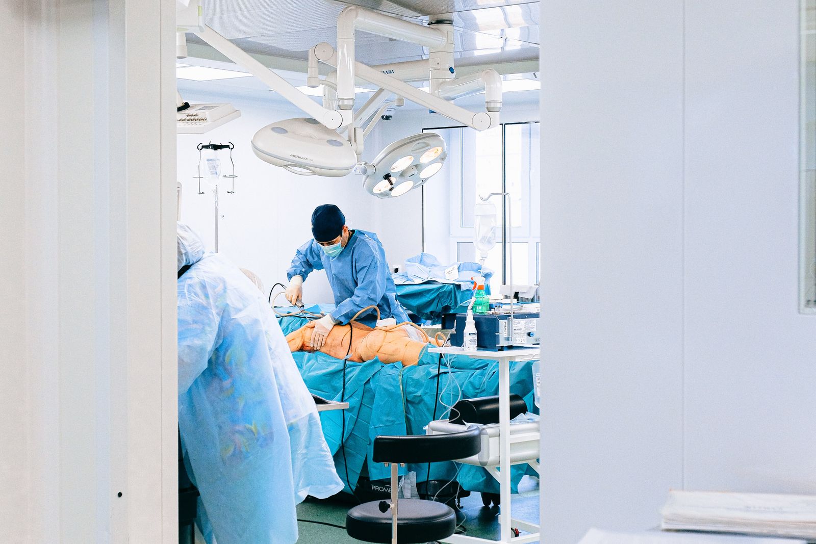 Surgeon operating on a prepared patient in a bright theatre, the practice trauma surgery expert witnesses examine